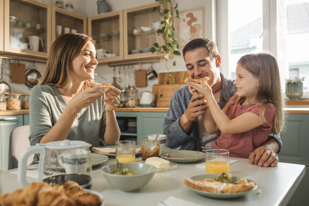 Young parents and their daughter talking while having breakfast.